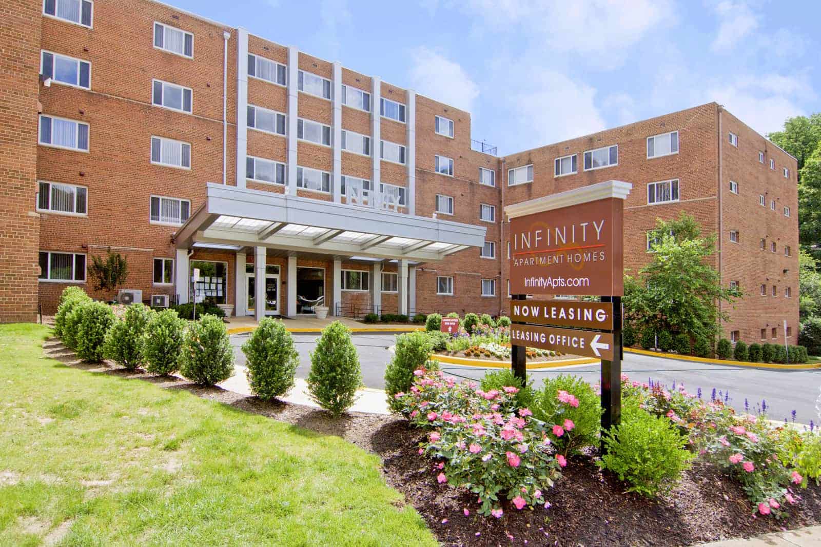 Entrance to the apartment building with a directional sign to the leasing office in the foreground.