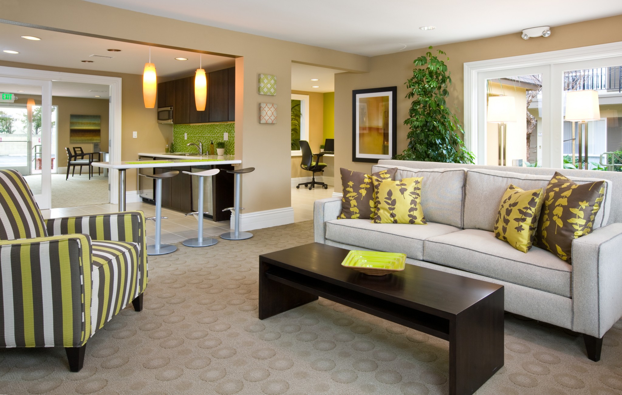 View of the clubhouse with living room set up and kitchen and office area in the background.