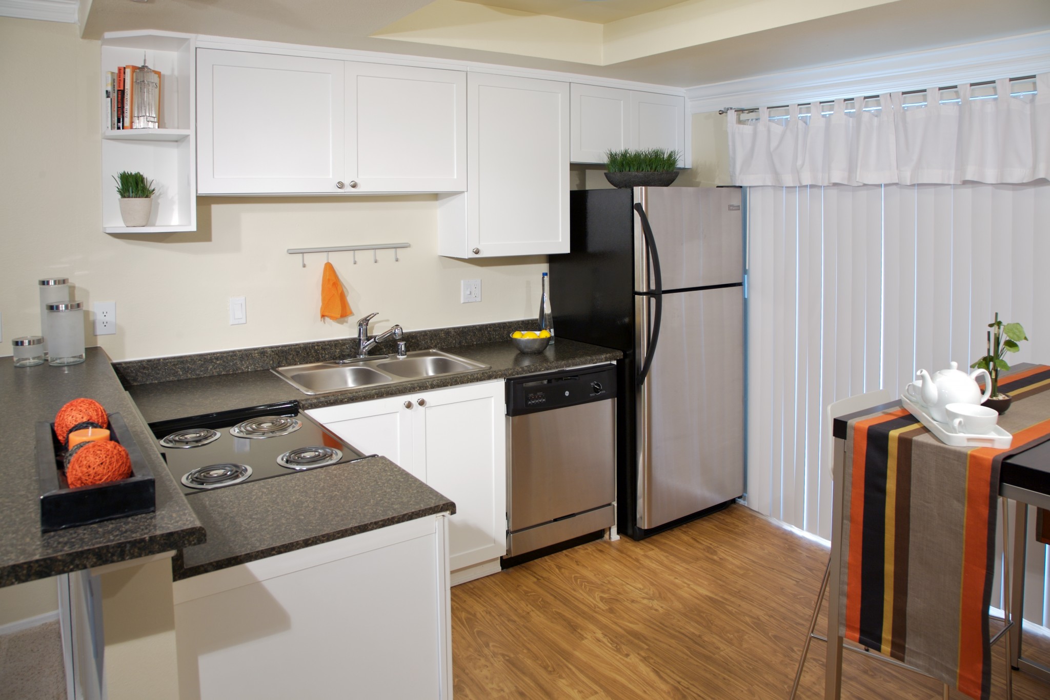 Apartment kitchen with stainless steel appliances, black countertop and white cabinets..