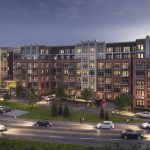 Wide exterior of apartment complex with roadway and parking lot in foreground