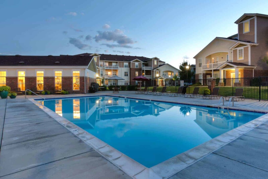 Exterior of swimming pool with apartment complex in background.