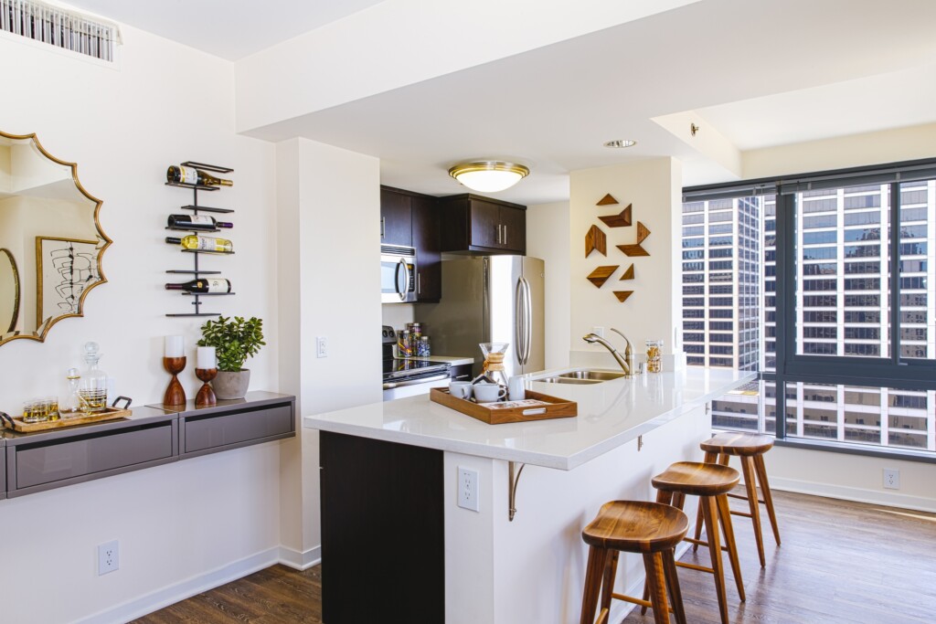 White kitchen with countertop bar, barstools and stainless steel appliances.