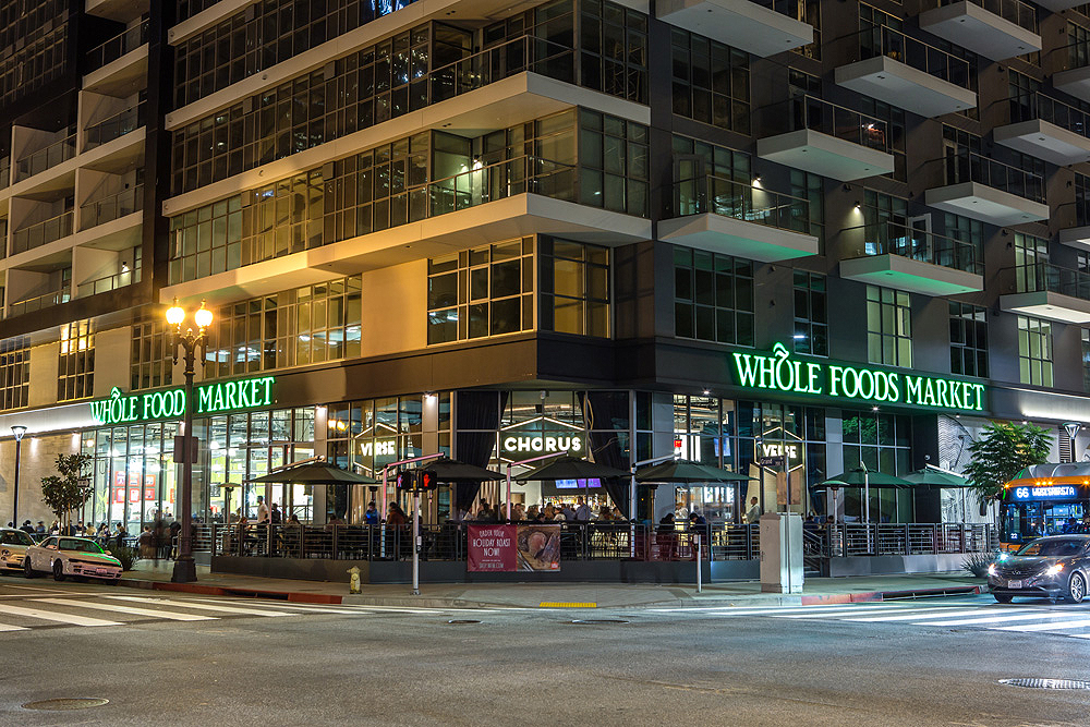 Street-level exterior of corner of apartment building showing Whole Foods Market on ground floor.