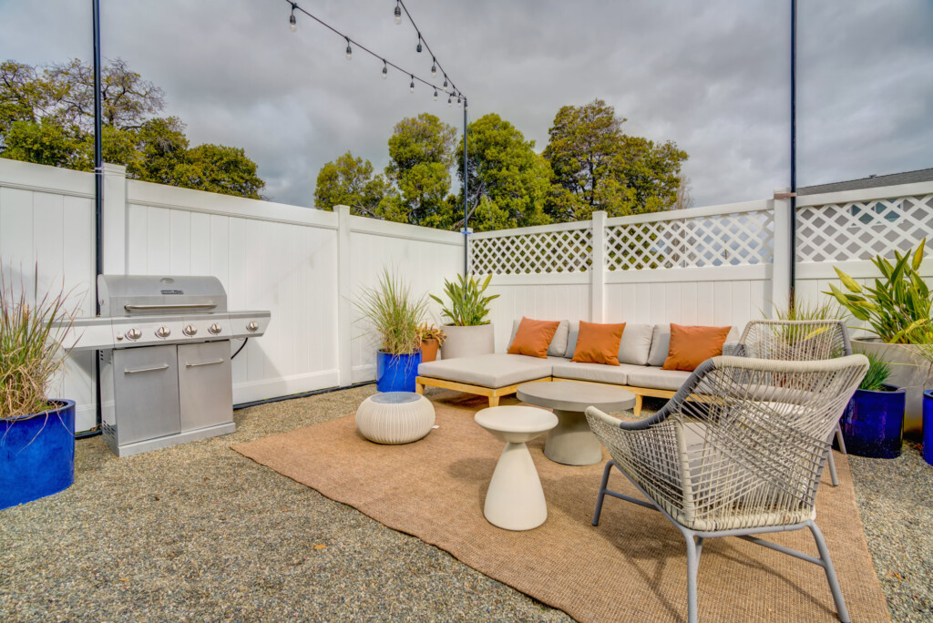 Apartment exterior sitting area with low couch, BBQ and latticed fence