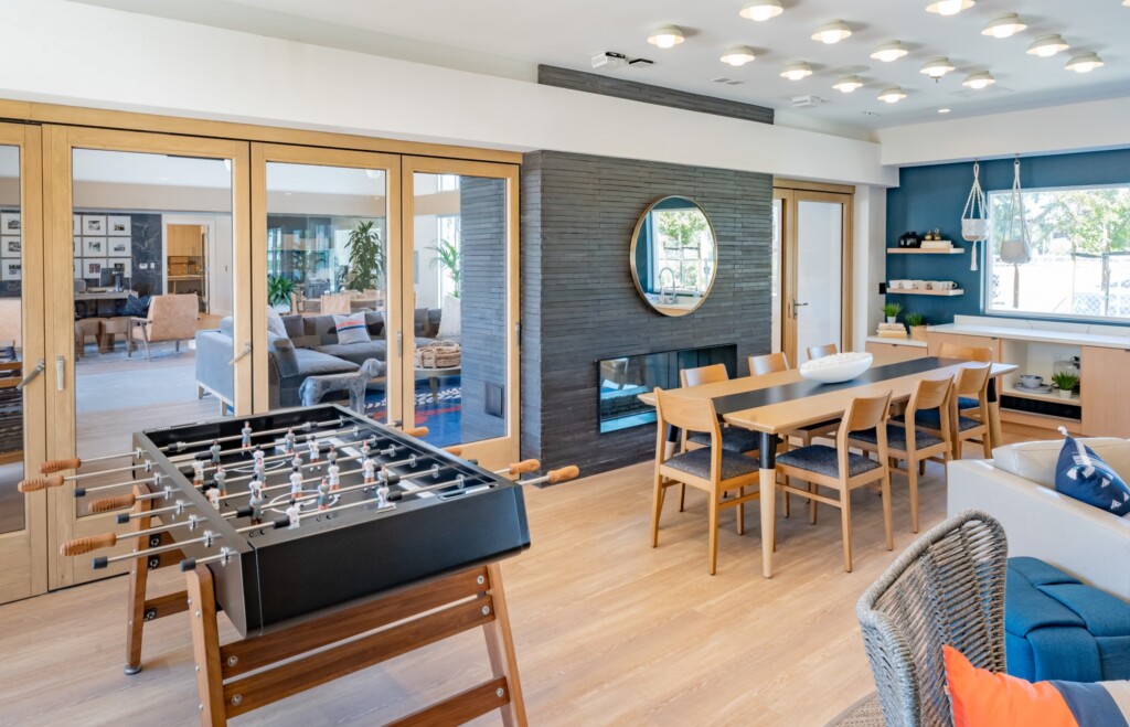 Interior with foosball table, large table and chairs, and fireplace with french doors to another room with couches