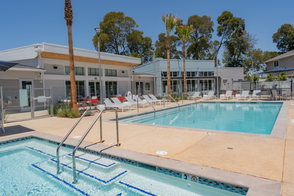 Exterior with two pools and lounge chairs with single-story buildings in background