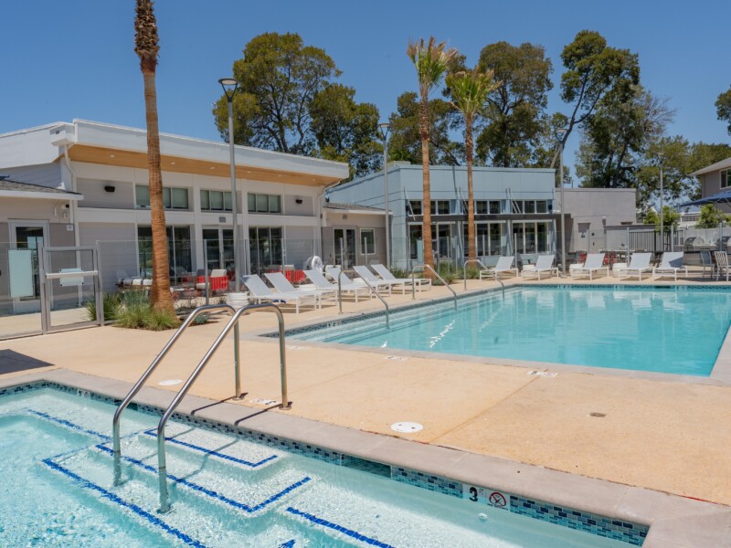 Exterior with two pools and lounge chairs with single-story buildings in background