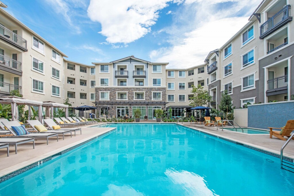 Exterior of apartment complex courtyard with pool, spa, lounge chairs and cabanas.