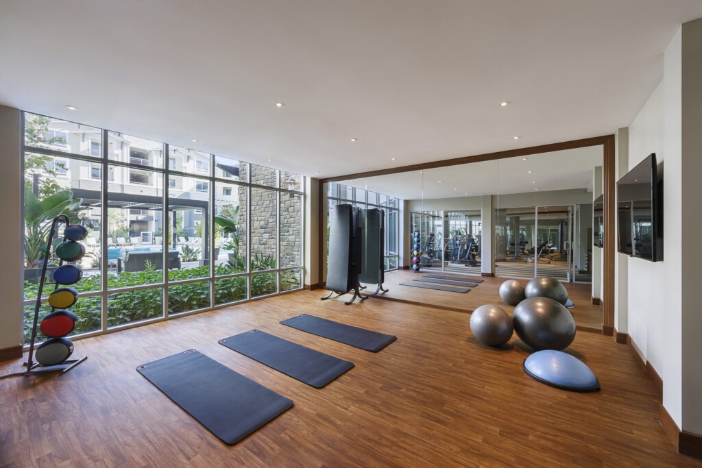 Interior of yoga studio with exercise balls, yoga mats and medicine balls in front of mirrored wall.