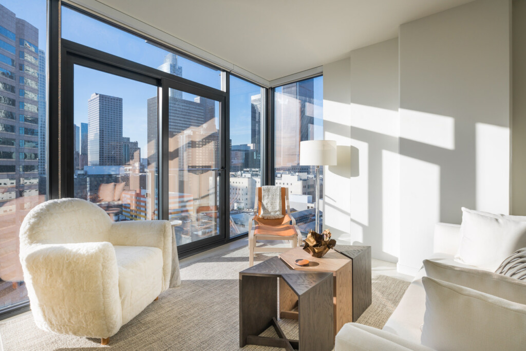 Interior of brightly lit, modern apartment with city views out floor-to-ceiling windows