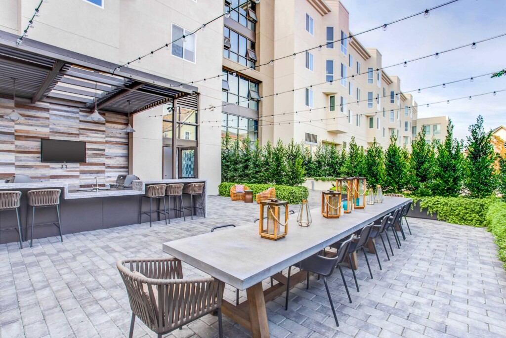 Exterior of apartment complex outdoor courtyard with long dining table and barbeque area