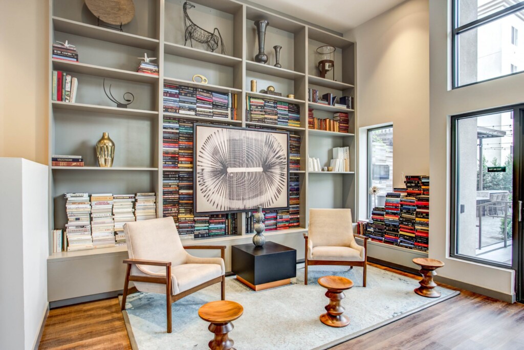 Common-area room with high ceilings, bookshelves and two modern chairs