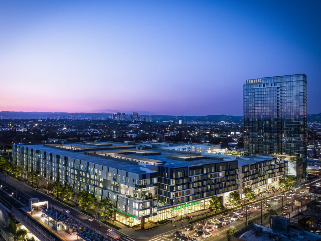 Aerial exterior of 6-story apartment complex filling city block and 14-story apartment tower