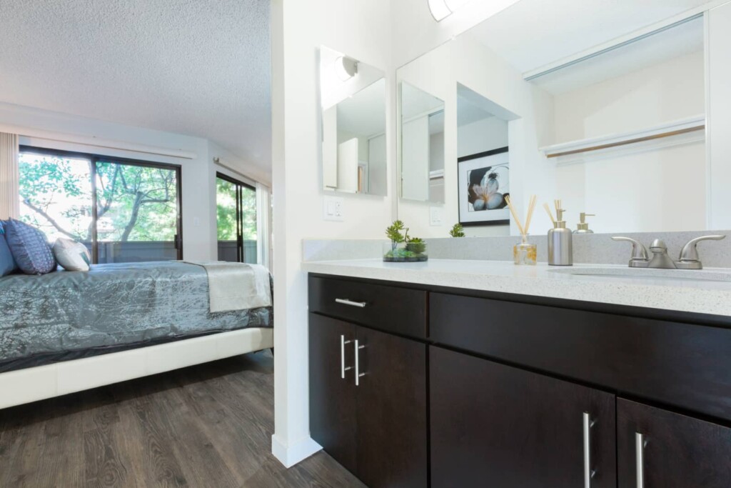 Open plan bedroom with bathroom vanity in foreground and bed in background.