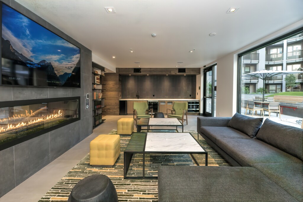 Interior common space with couches, chairs and sleek, glass enclosed fireplace overlooking interior courtyard.
