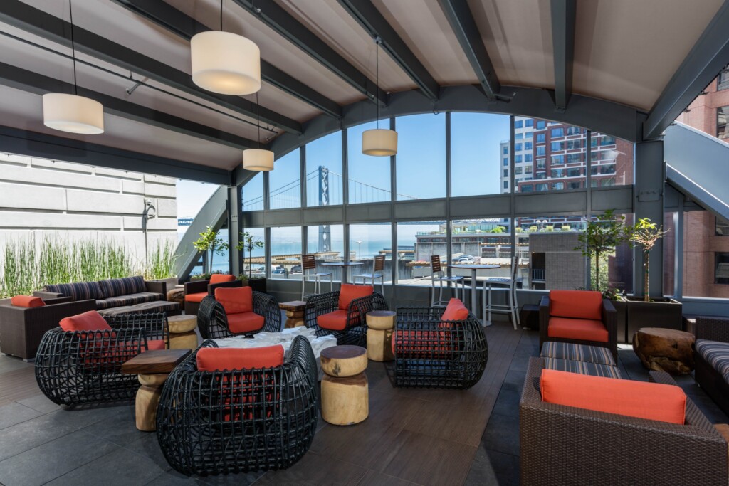 Covered outdoor area with chairs and tables with a view of the San Francisco Bay Bridge.