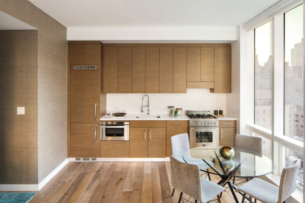 Interior of modern open kitchen with dining table and large wall of windows.