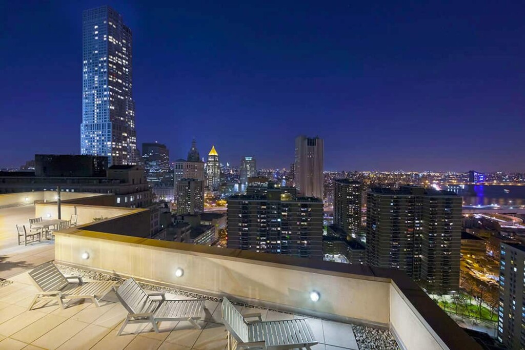 Exterior of rooftop with lounges amidst downtown New York buildings