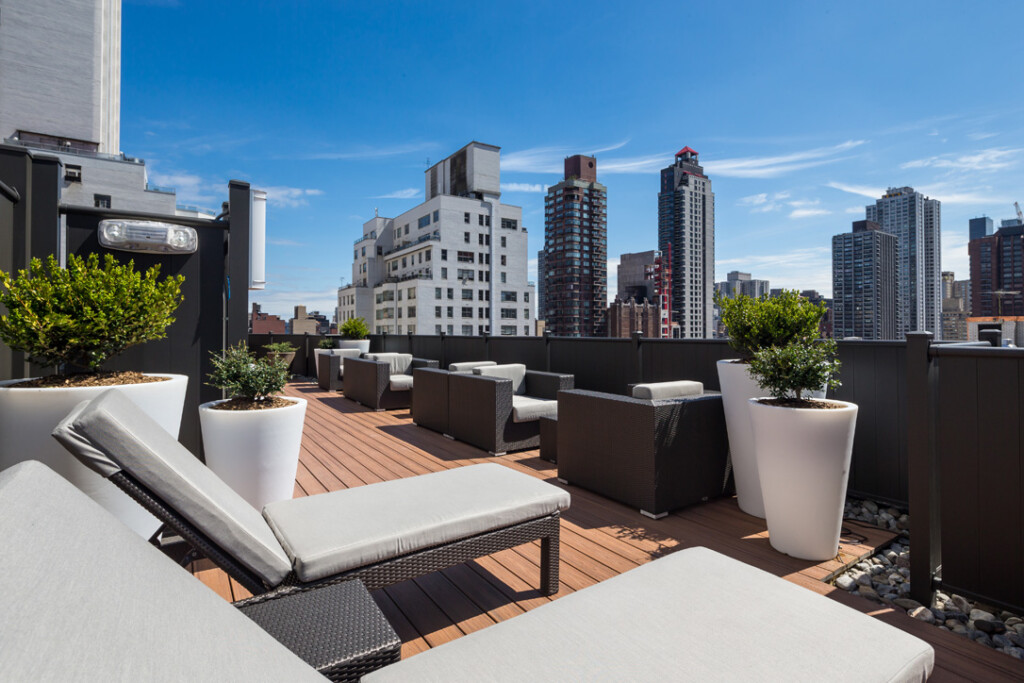Exterior of outdoor courtyard with lounge chairs, side tables and views of the city.
