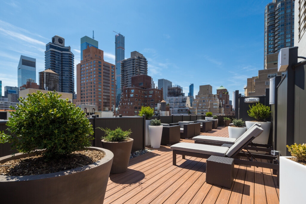 Exterior of roofdeck with lounge chairs, planters and a view of the city in the background.
