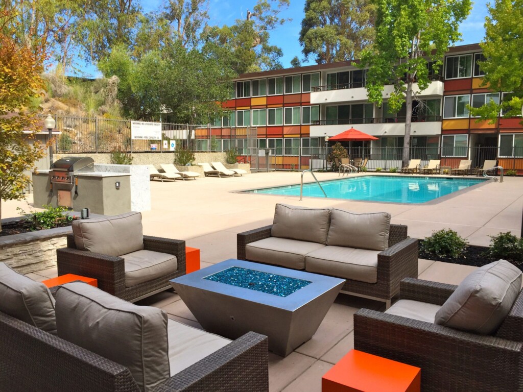 Exterior of pool deck with modern outdoor couches with fire pit in the foreground.