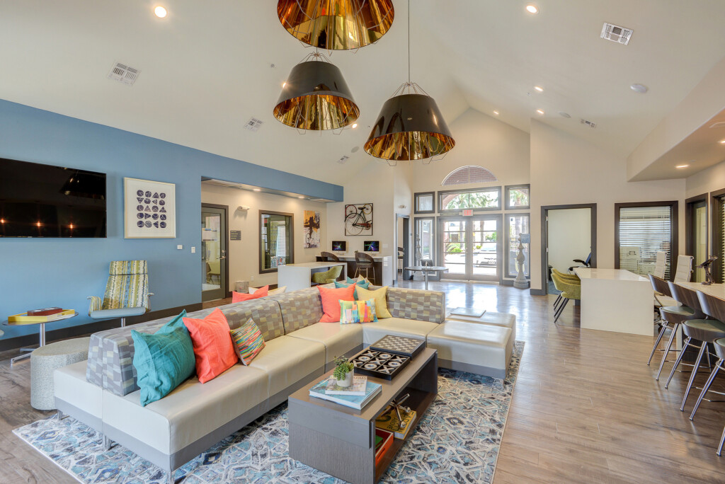 Interior of large, open common area with couches, tables, bar stools and large flat-screened television