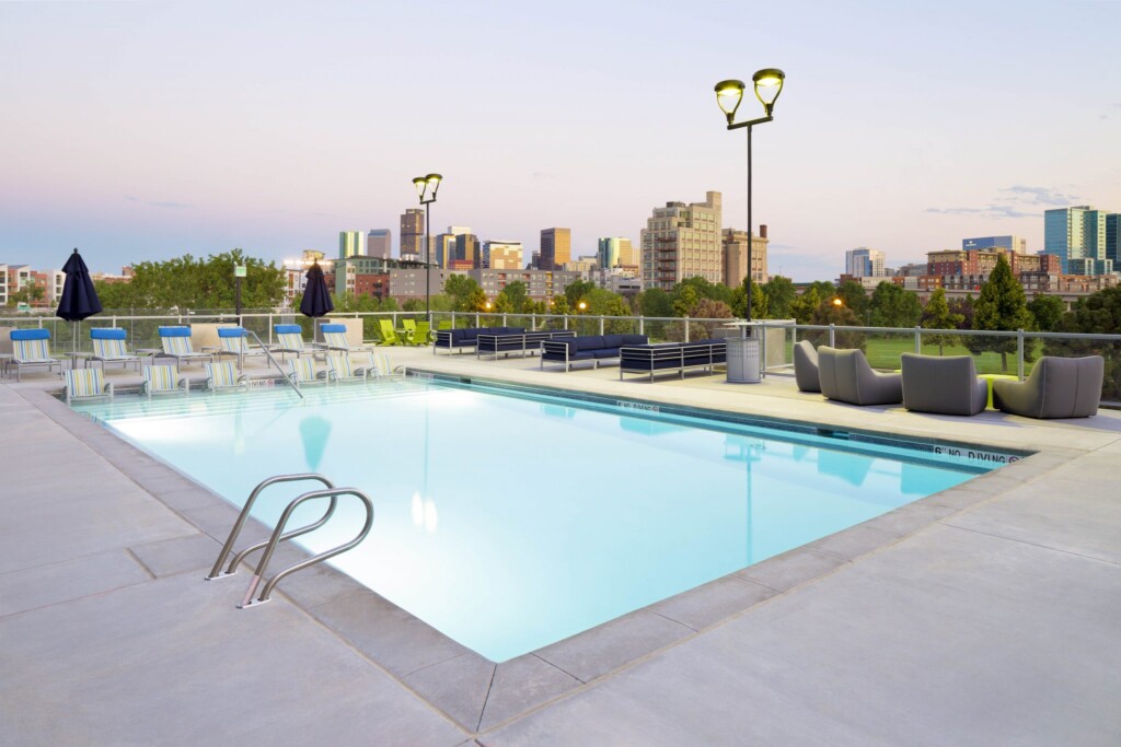 Rooftop pool surrounded by seating with downtown skyline in background.